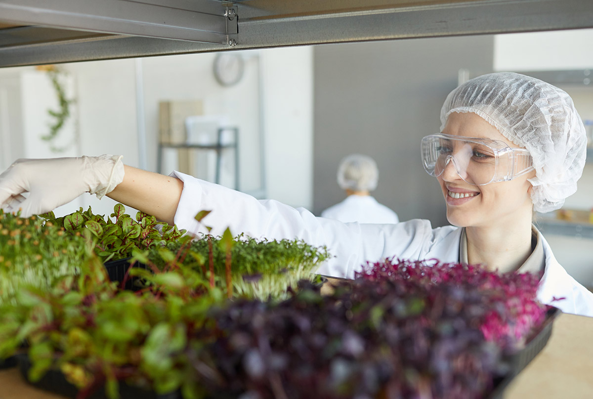 portrait-smiling-female-scientist-examining-plant-samples-while-working-biotechnology-laboratory-copy-space